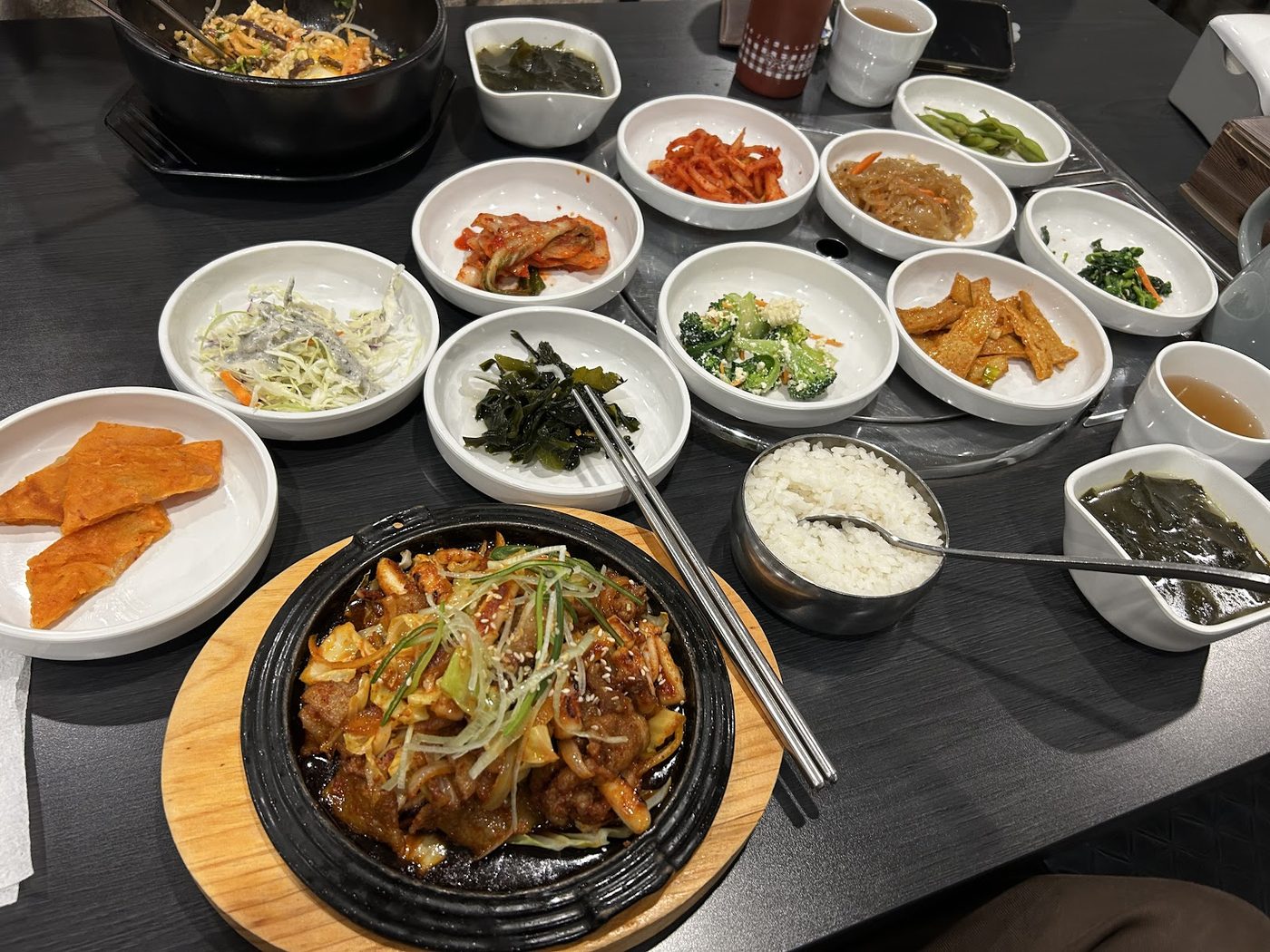 A hot Korean dish surrounded by rice and small side dishes