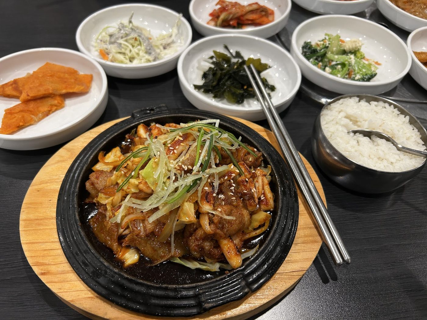 A hot Korean dish with rice and several small side dishes